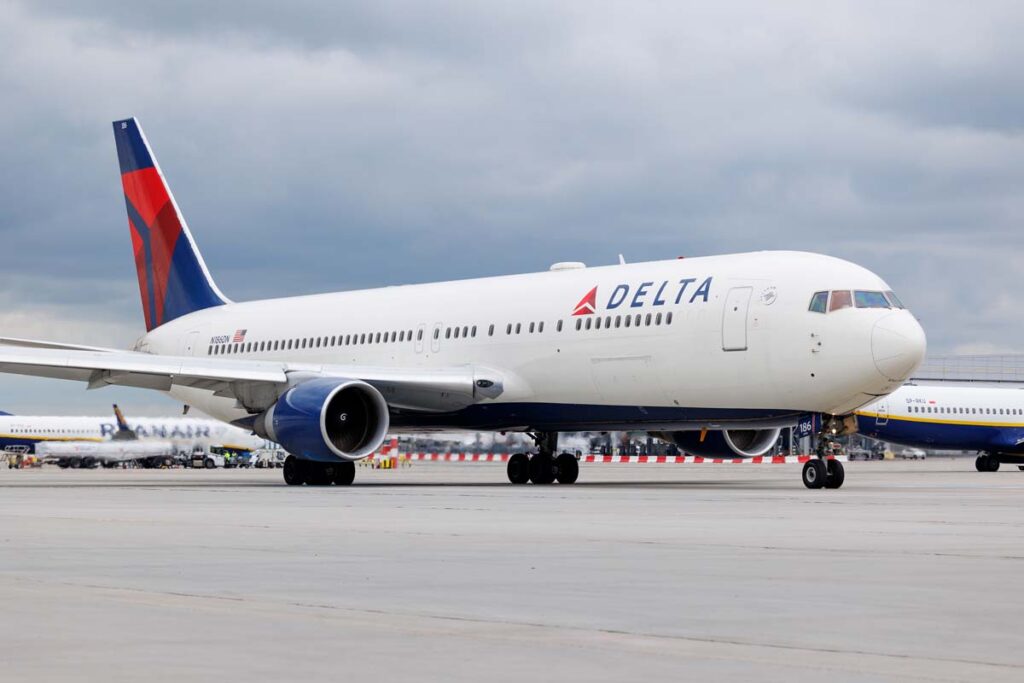 A Delta airlines plane on a tarmac at an airport, representing DOJ probe into Delta flight cancellations.