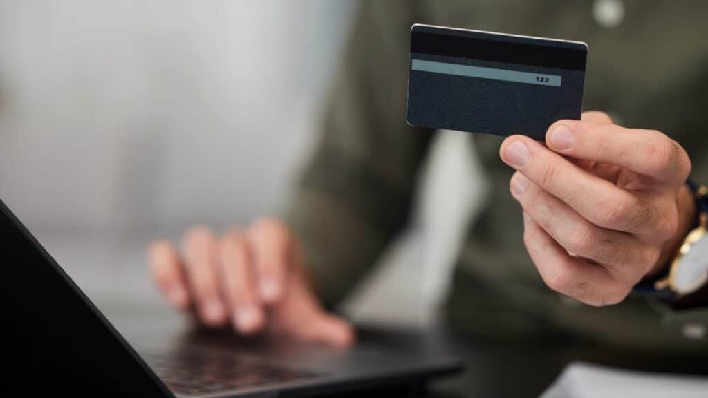 Online shopping: Man holding credit card and entering it into laptop.