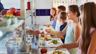 School children in line for food at the school cafeteria, representing school lunch payment junk fees.