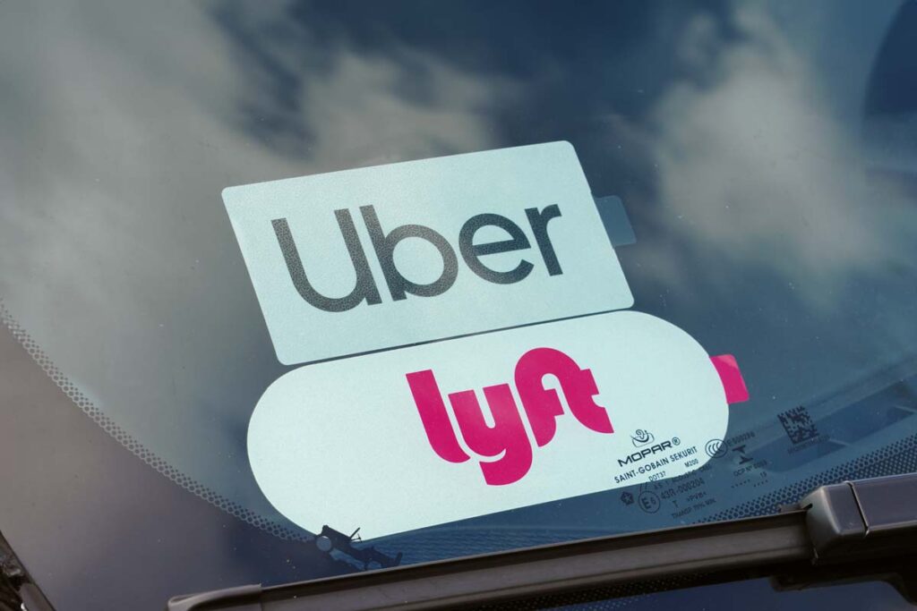 Close up of Uber and Lyft sticker in a car window, representing the Uber and Lyft settlement.