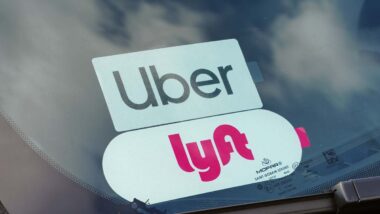 Close up of Uber and Lyft sticker in a car window, representing the Uber and Lyft settlement.