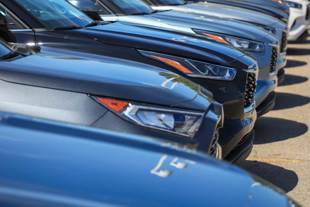 Close up of a line of luxury cars in a parking lot, representing July auto recalls.