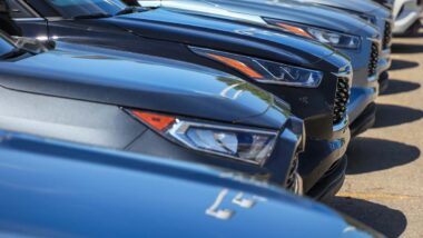 Close up of a line of luxury cars in a parking lot, representing July auto recalls.