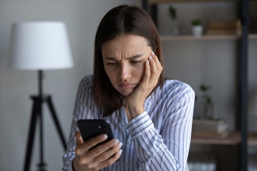 An irritated woman reading a text on her smartphone, representing the unsolicited text messages class actions.