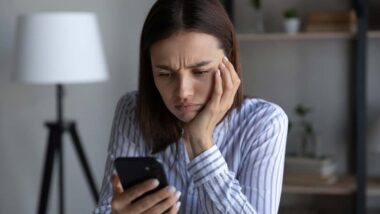 An irritated woman reading a text on her smartphone, representing the unsolicited text messages class actions.