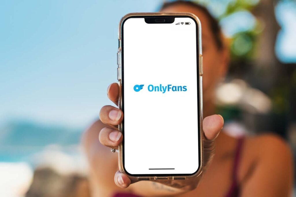 Close up of a woman holding a smartphone with the OnlyFans logo displayed, representing the OnlyFans class action.