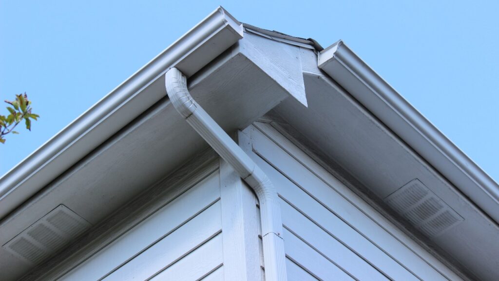 Gutters on a house corner, blue sky background.