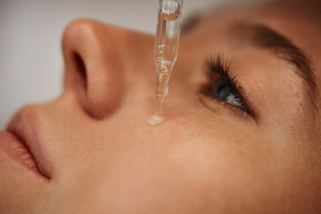 Close up of a woman putting a skincare serum on her face, representing the Pixi class action.