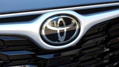 Close up of a Toyota emblem on a front bumper, representing the Toyota recall.