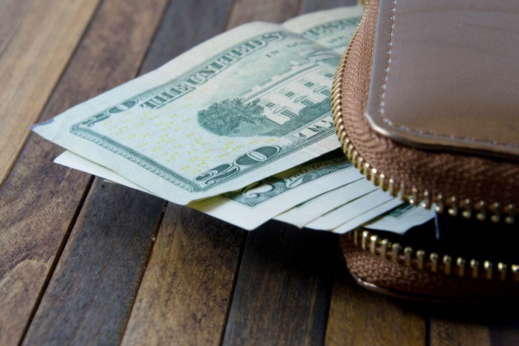 Close up of U.S. cash spilling out of a wallet, representing FTC refunds in June and July 2024.