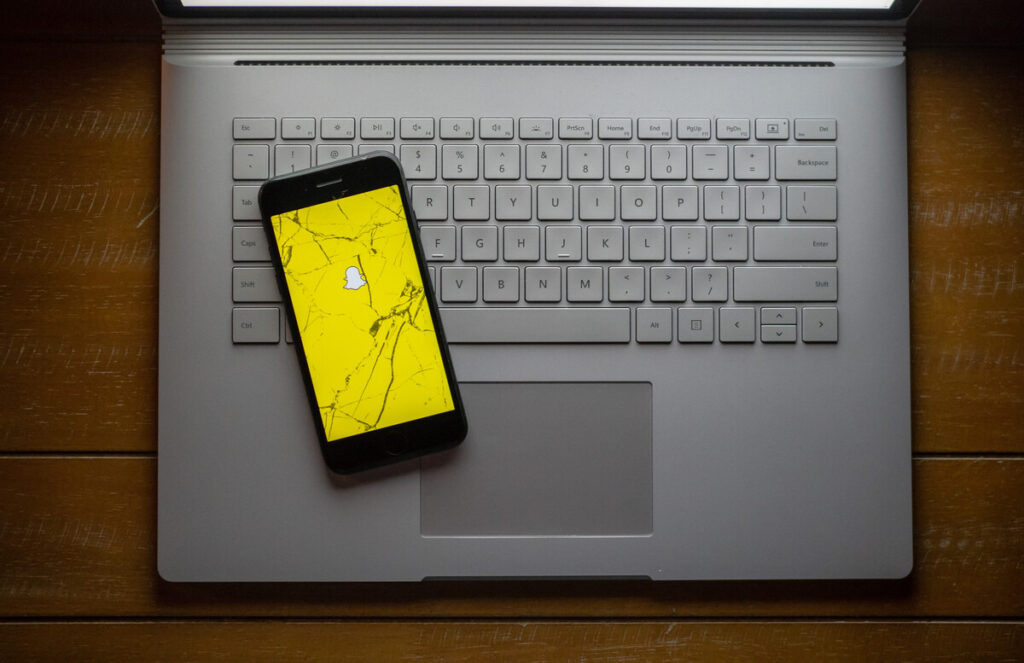Broken phone on computer with Snapchat app representing the Snapchat lawsuit.