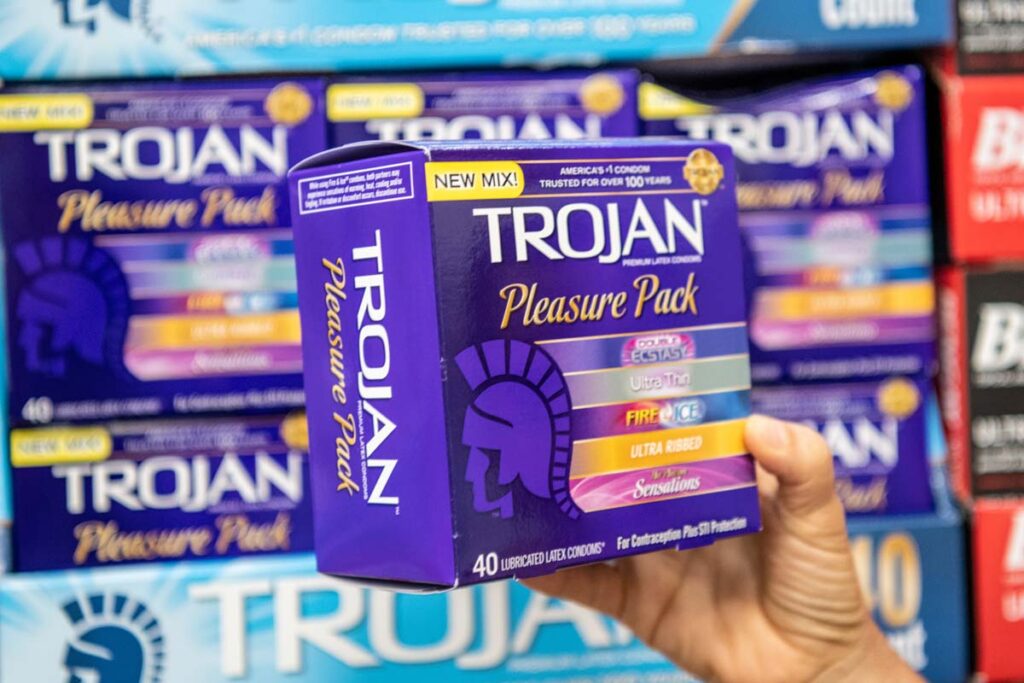 Close up of hand holding a Trojan variety pack box, representing the Trojan condoms class action.