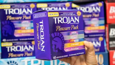 Close up of hand holding a Trojan variety pack box, representing the Trojan condoms class action.