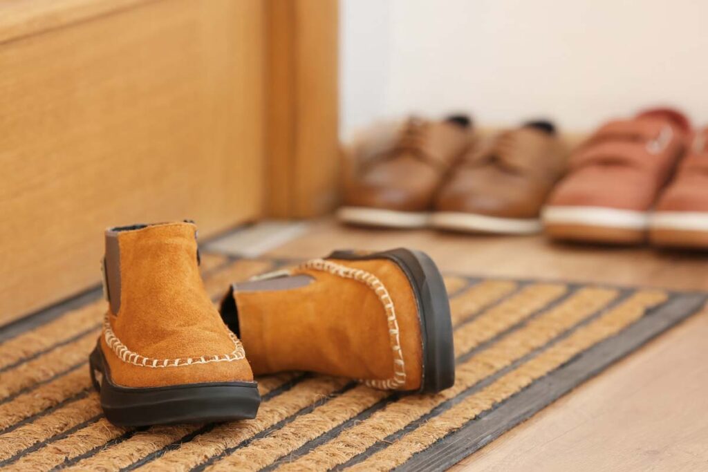 Close up of childrens shoes next to a door, representing North Carolina foster care.