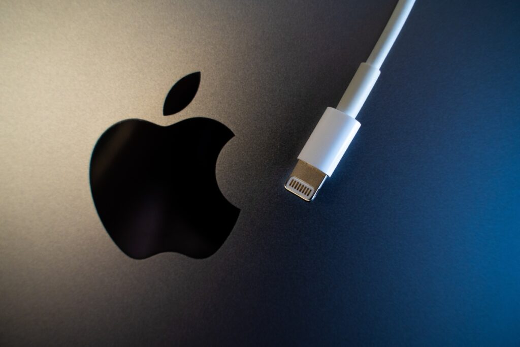 An Apple logo with a lightning charger next to the logo representing the Apple class action.