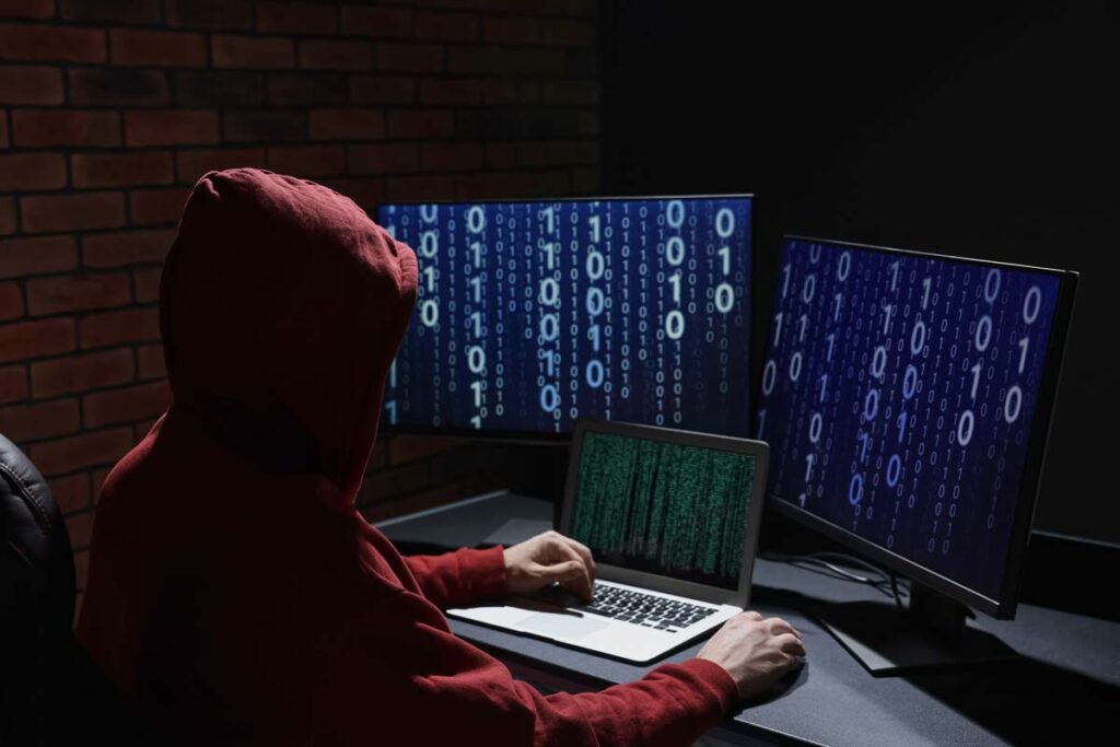 A hooded hacker using a computer, representing the data breach.