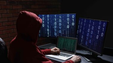 A hooded hacker using a computer, representing the data breach.