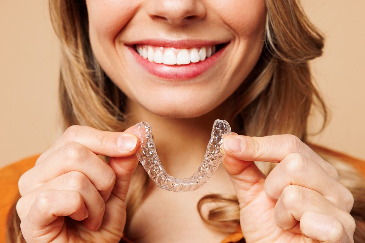 woman using invisalign silicone teeth trainer representing representing the Invisalign class actions.