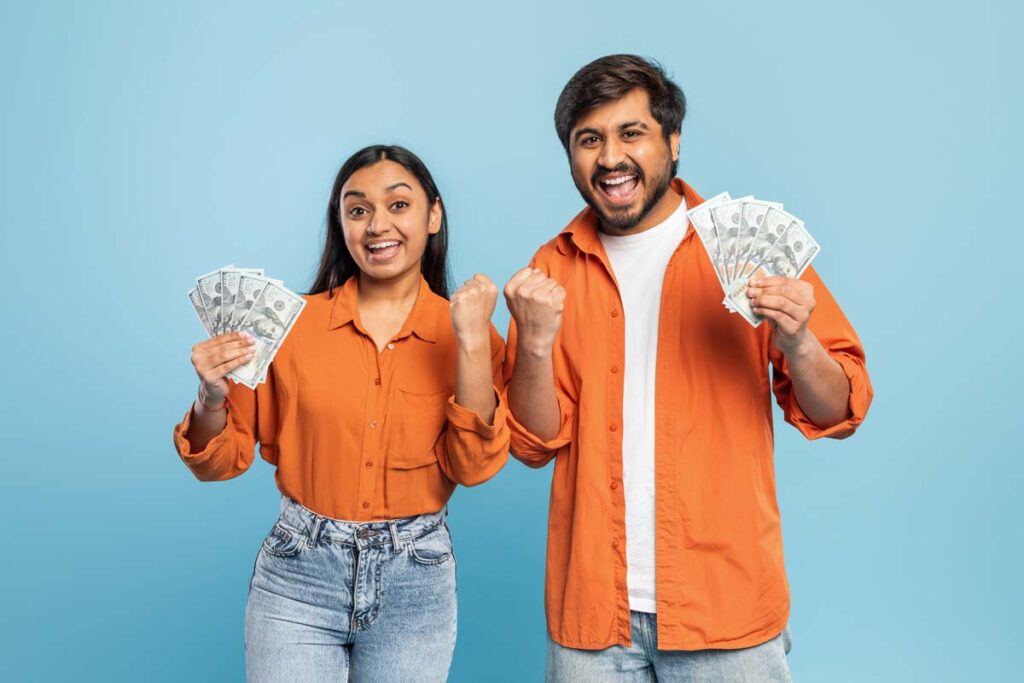 An excited couple holding cash, representing recent class action rebates.