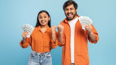 An excited couple holding cash, representing recent class action rebates.