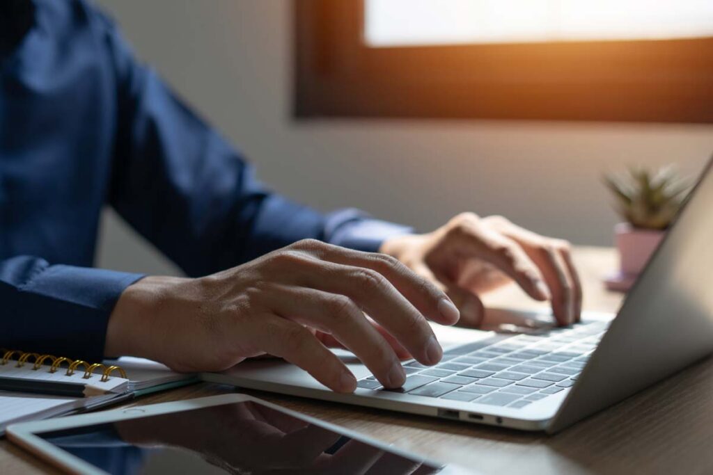 Close up of a mans hands typing on a laptop, representing data privacy class actions.