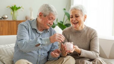 Retirement savings concept older couple saving with piggy bank.