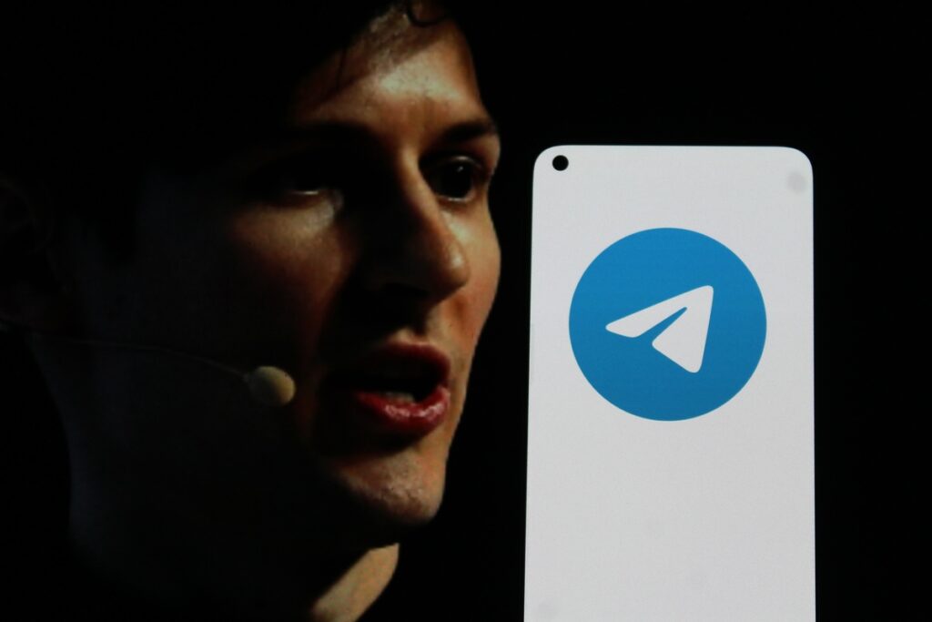 CEO of Telegram next to a Telegram logo on a cell phone representing the Telegram CEO indictment.