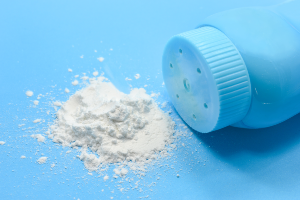 Talcum powder spilled from a baby powder container on blue surface