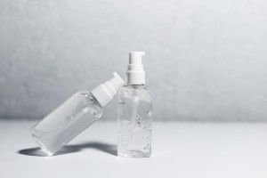 Bottles of clear hand sanitizer against a grey background