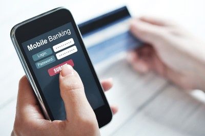 Person holding credit card and smartphone showing mobile banking login screen