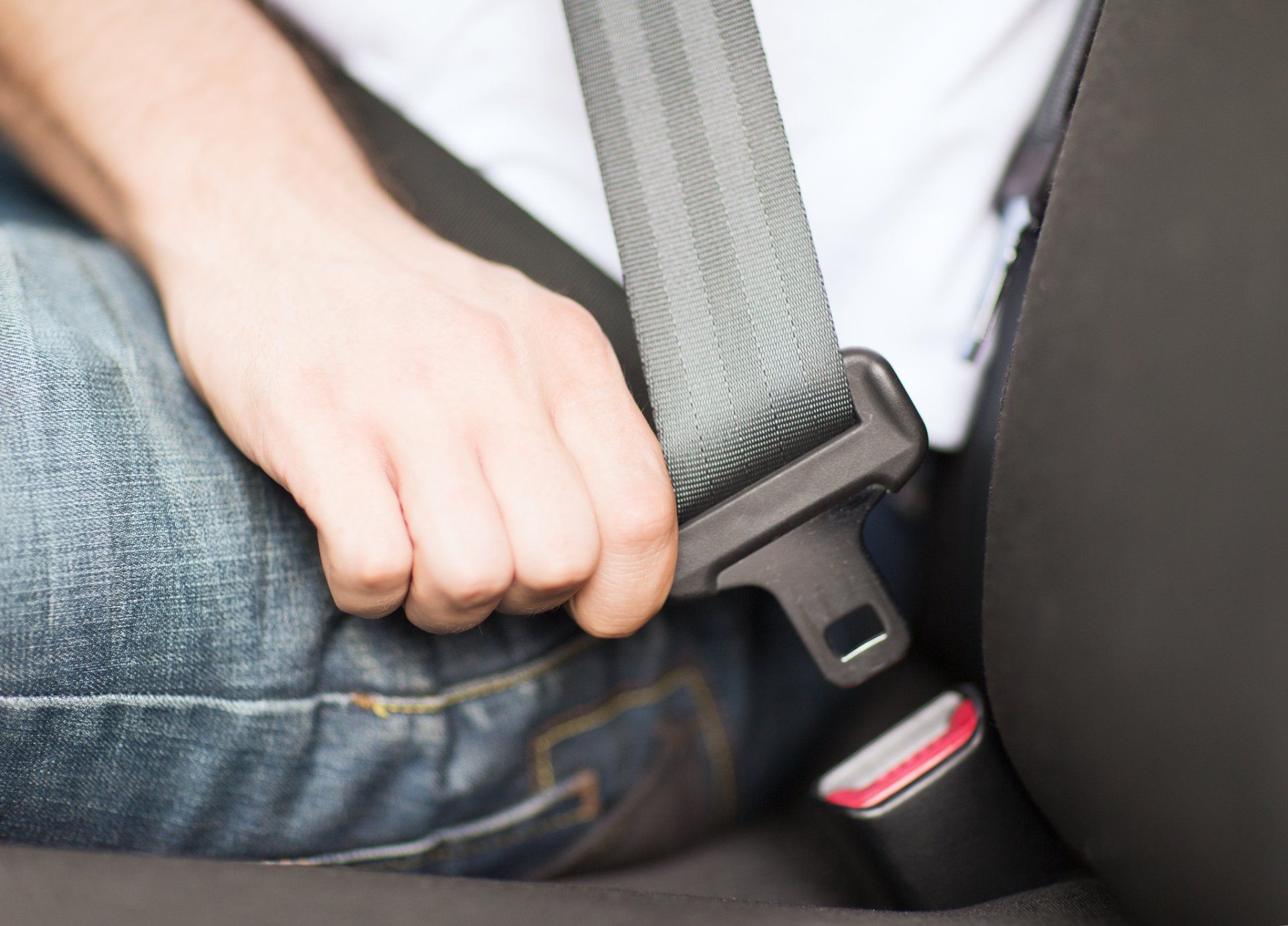 Person fastens seat belt in front seat of car