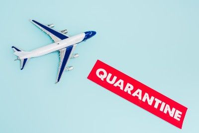 Model of airplane next to red sign that reads "quarantine" - travel to Spain