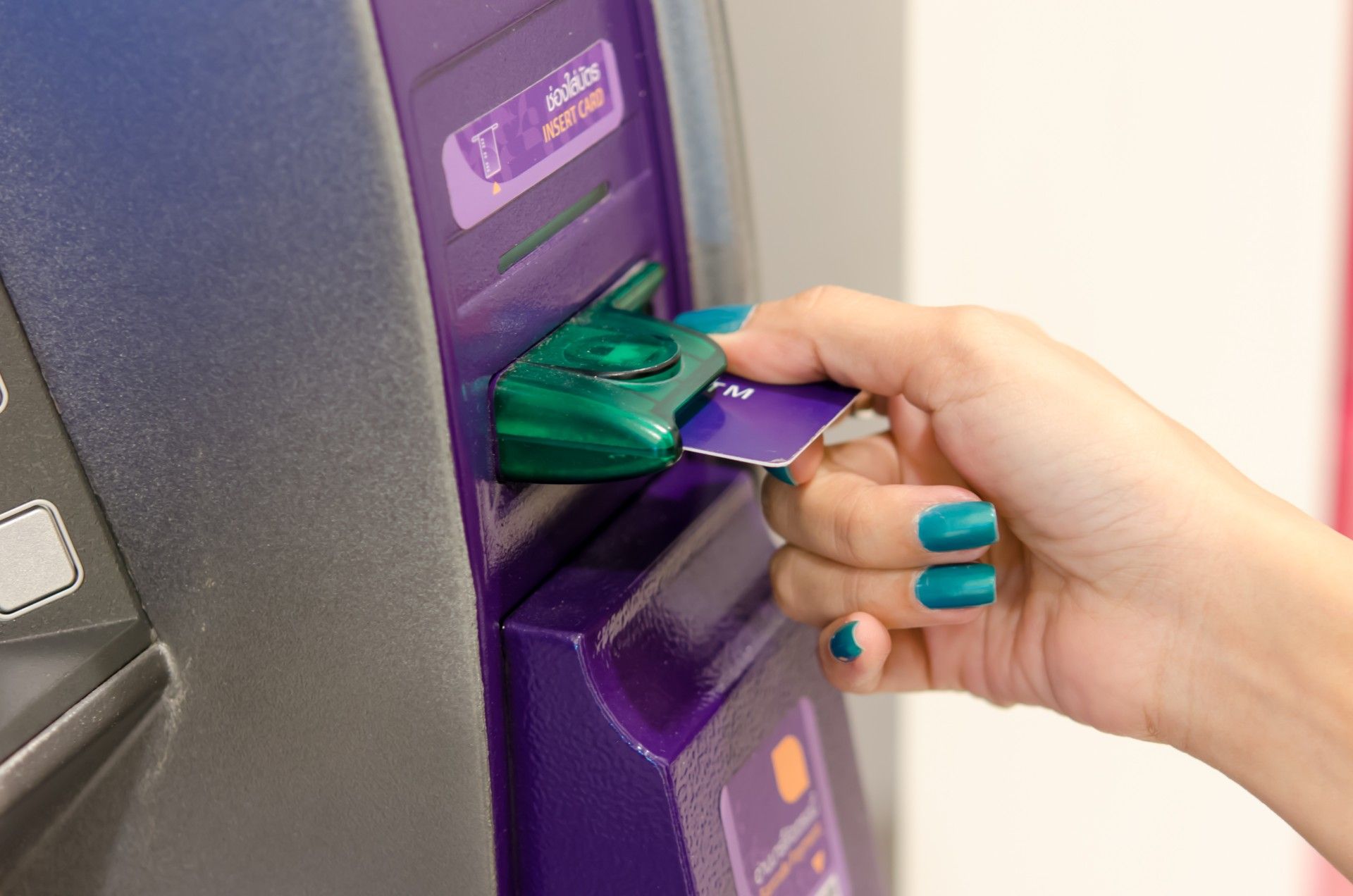 Woman inserts card into ATM - New rules for UK cash machines