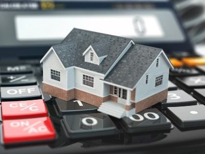Model of house sits on desk calculator - mortgage holiday
