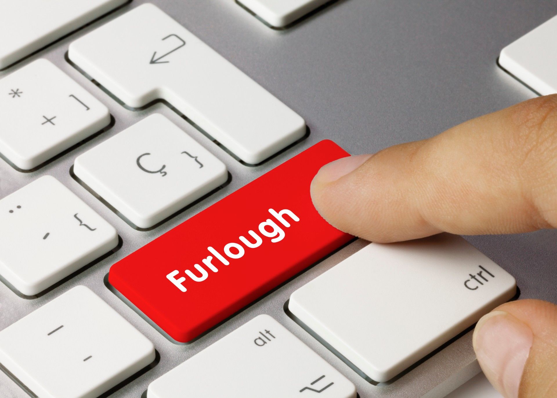 Man presses red "furlough" button on computer keyboard - furlough scheme