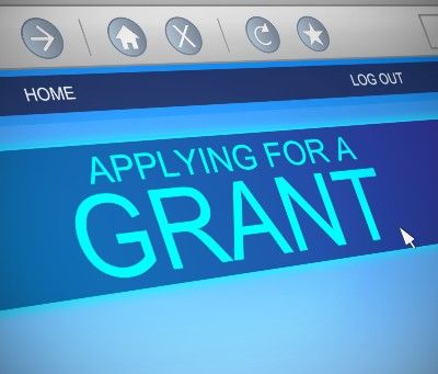 Computer screen displays website with "Applying for a grant" in blue banner - self-employment grant