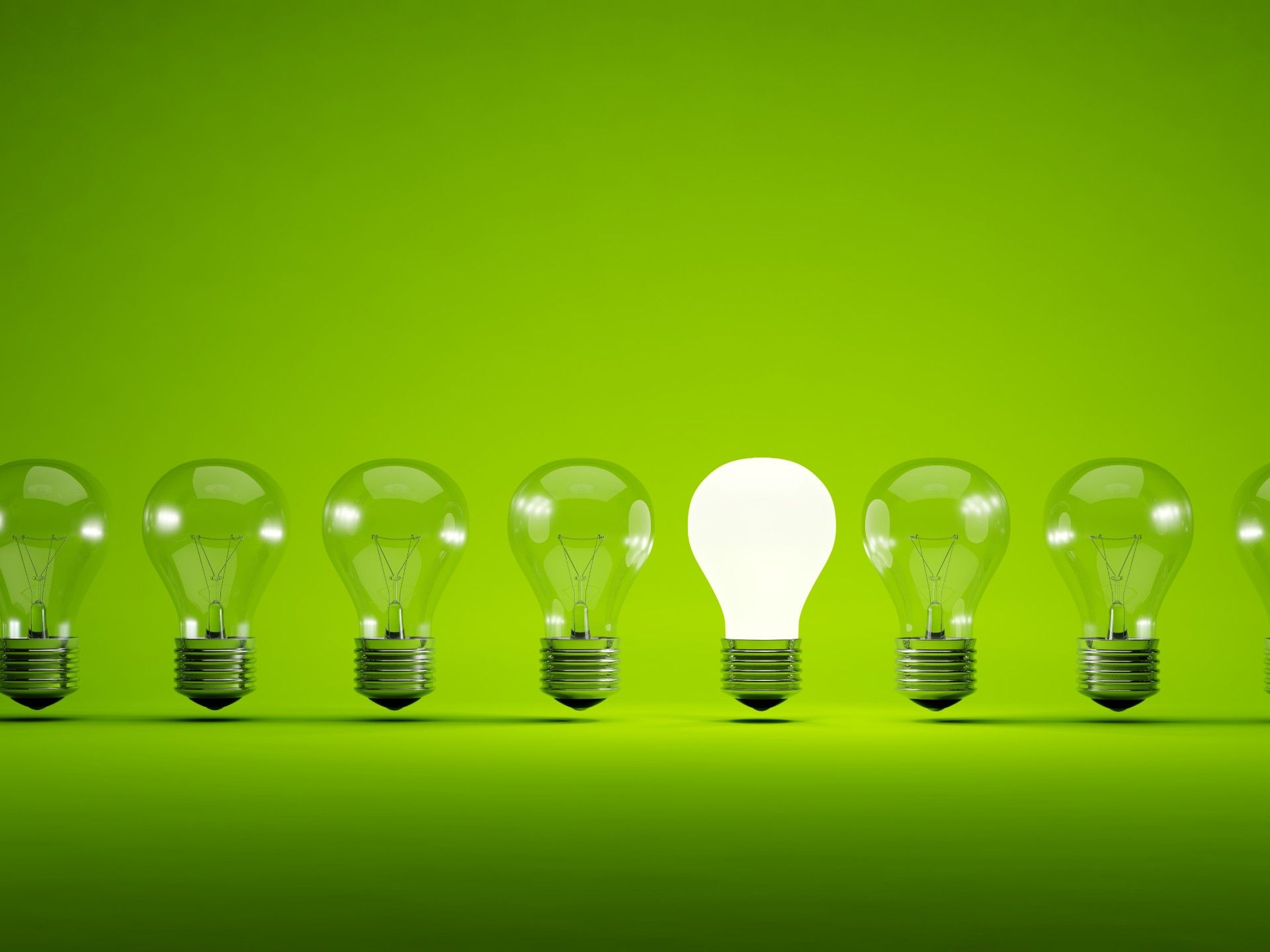 One in a row of lightbulbs is lit up against a green background - Bulb