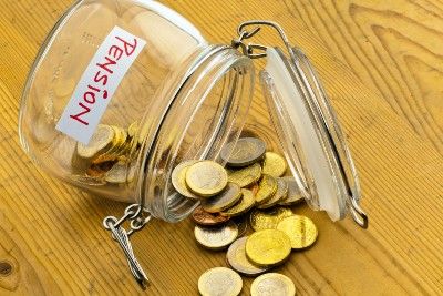 A glass jar with a "pension" label is knocked over, with coins spilling out - pension scams