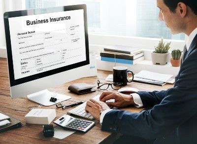 Man sits at work desk with a business insurance form on his computer screen - fca test case