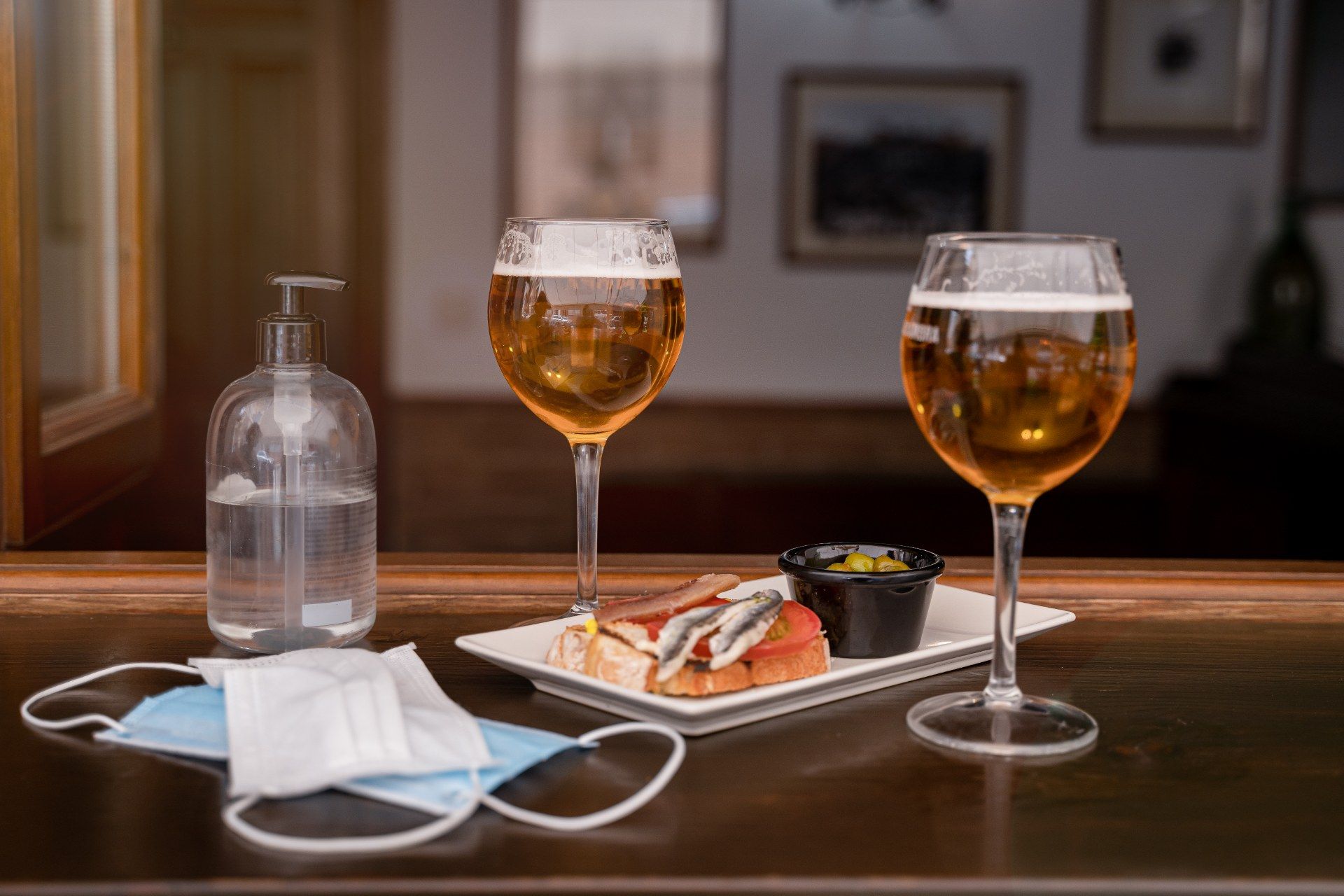 Food, two glasses of beer and personal protective equipment on a bar - pub curfew