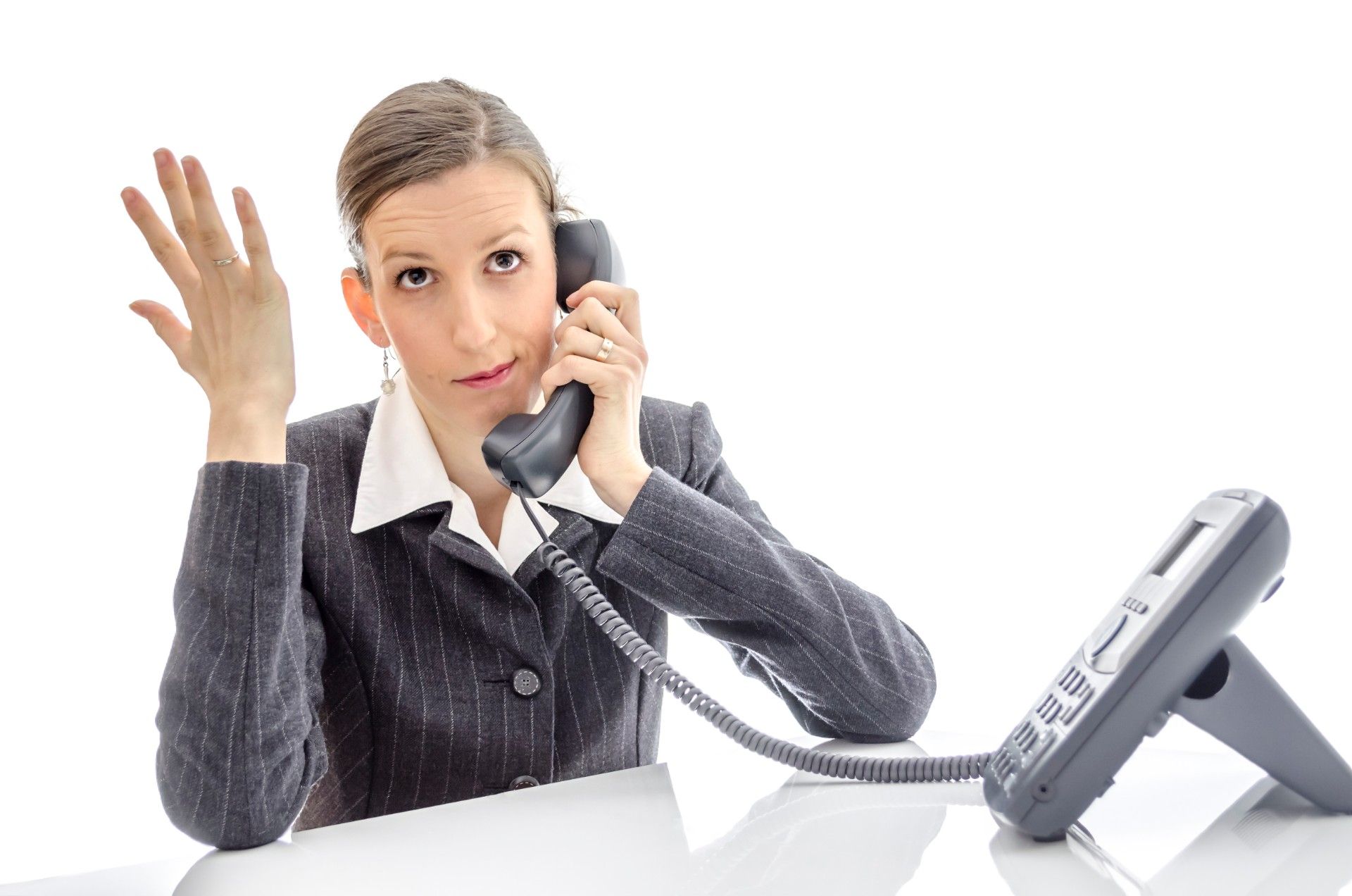 Annoyed woman in suit talking on desk phone and gesturing - pension cold calls