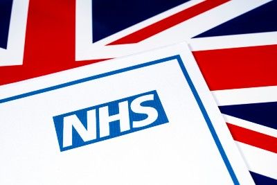 Card with NHS logo lies on top of UK flag - NHS workers