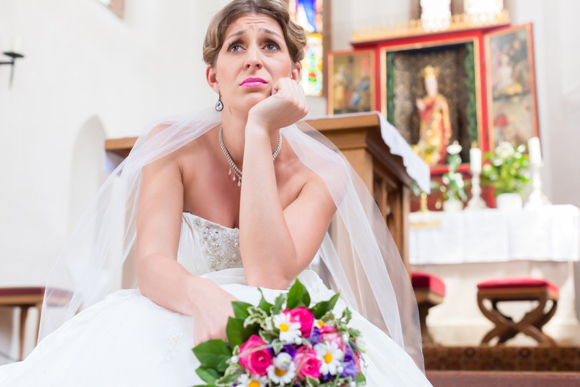 Sad bride sits in church with head on hand - cancelled wedding