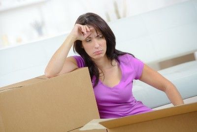 Sad woman sits with boxes as she's preparing to move - payment deferrals