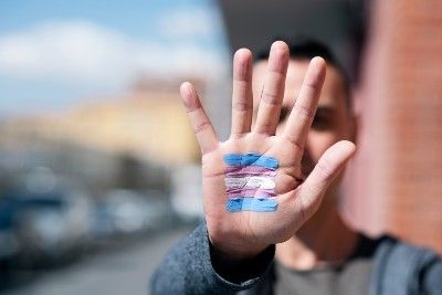 A person holds out their hand with a trans pride flag painted on the palm - gender recognition