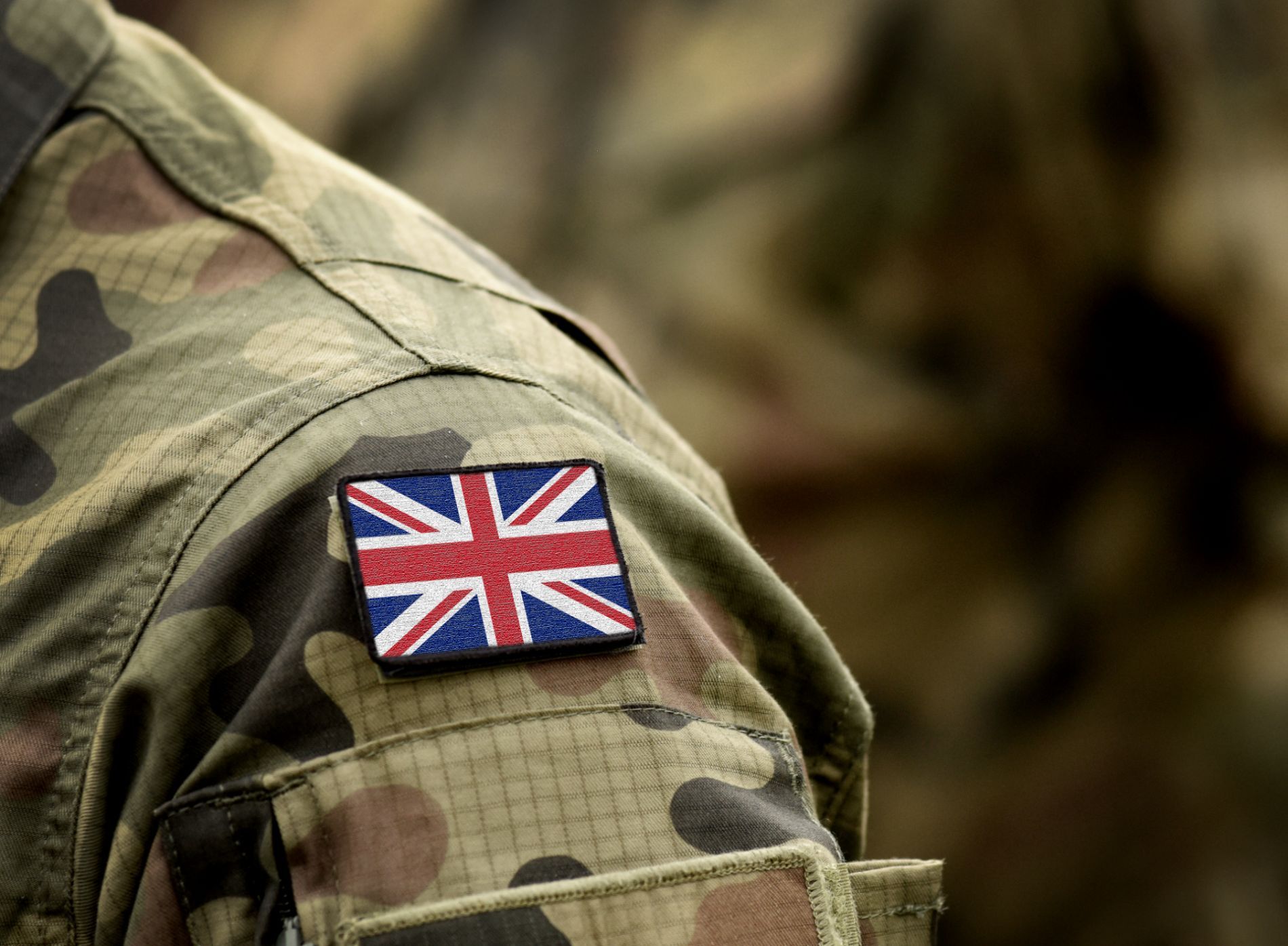 Closeup of a soldier in uniform with UK flag patch on his shoulder - commonwealth veterans
