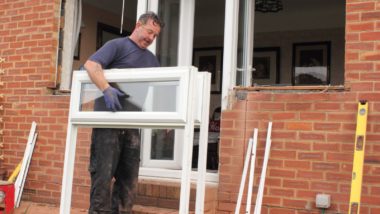 A man installs new windows on a brick house - double-glazing firms