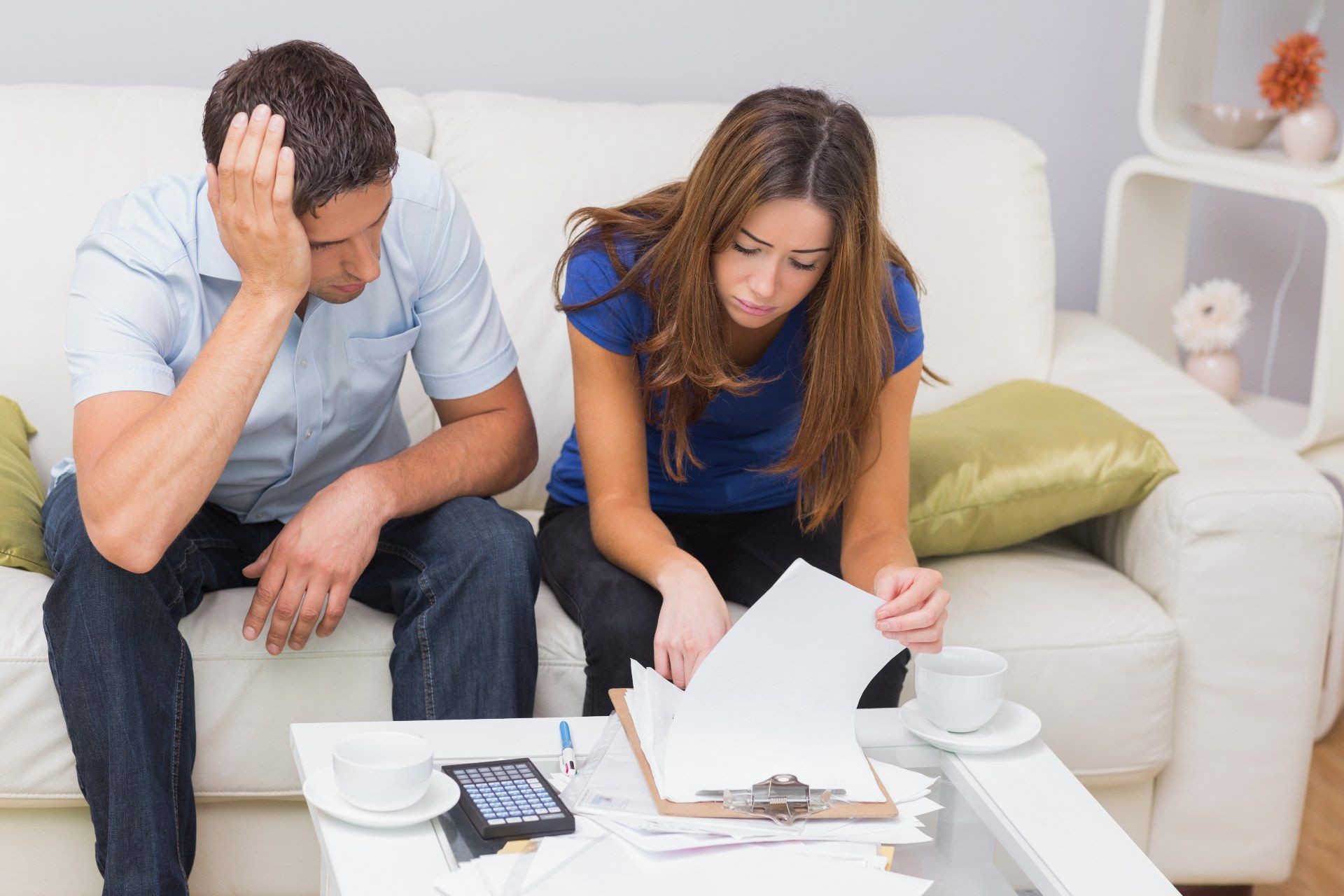 A man and woman sit on a sofa while going over bills - mortgage holiday