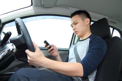 A male driver uses a mobile phone while not looking at the road - mobile phone driving ban