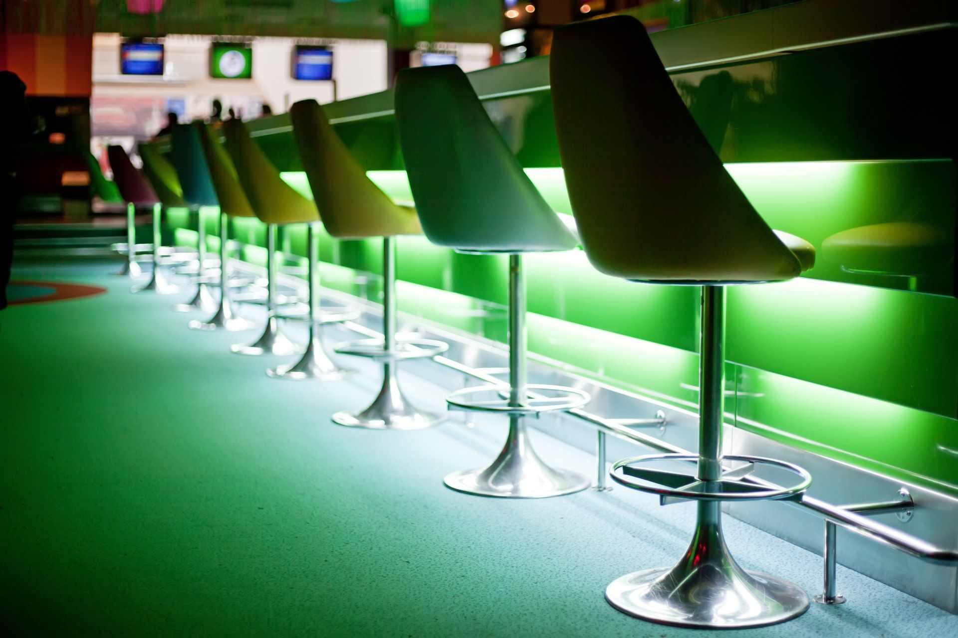 Chairs at a bar with green lighting sit empty - pub curfew